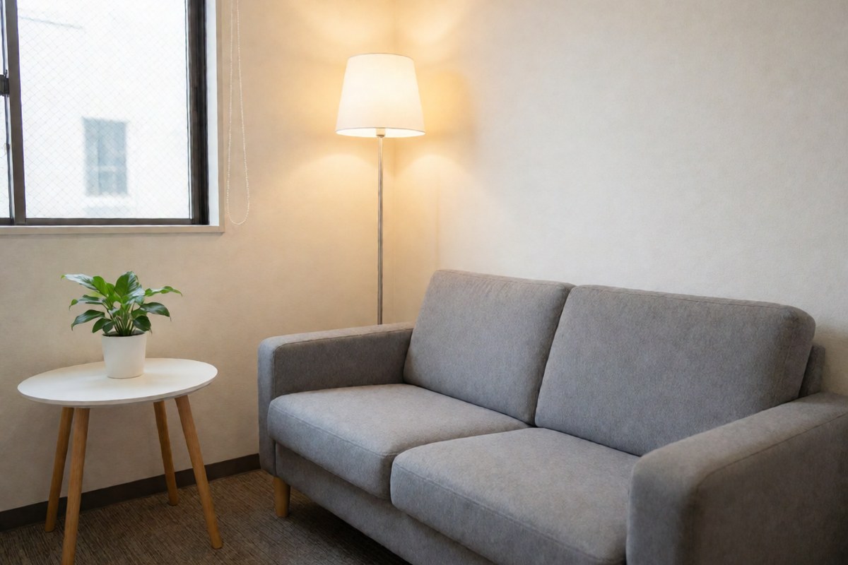 Gray sofa, floor lamp and plant in a calm waiting room near a front desk